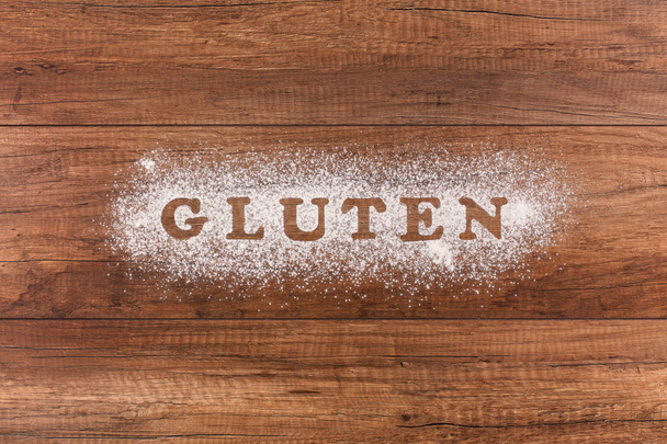 Gluten - słowo napisane w mąki na drewniany blat - dół widok, miejsce - Zdjęcie, obraz