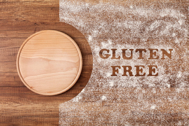 glutenfreie Wörter geschrieben in speziellem Mehl auf Holztisch gestreut - Ansicht von oben, Kopierraum - Foto, Bild