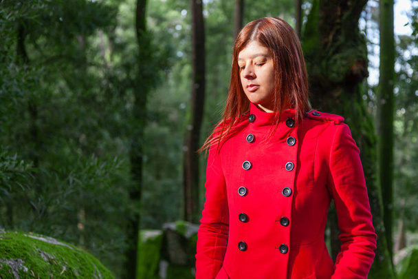 Genç kadın yalnız kırmızı uzun ceket veya palto giyen orman yolu üzerinde yürüme üzgün. Kız parça Doğa Park ormanda yürüyüş sırasında sonbahar, sonbahar ya da kış geçer - Fotoğraf, Görsel