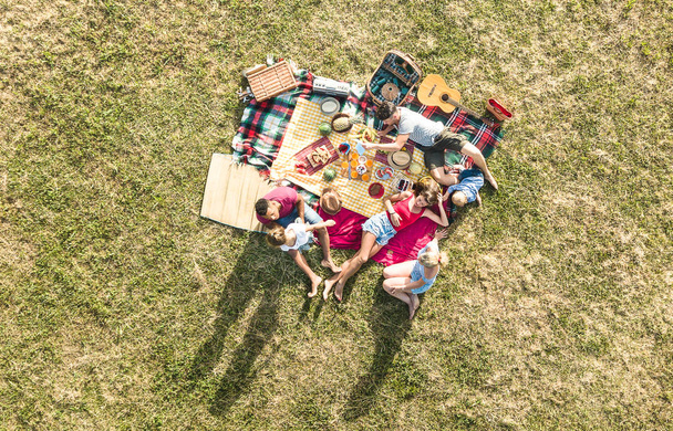 Widok anteny drone szczęśliwych rodzin, zabawy z dziećmi na piknik grill party - wielorasowe szczęścia i miłości koncepcja z mieszanej rasy ludzi bawi dzieci w parku - ciepły jasny filtr - Zdjęcie, obraz