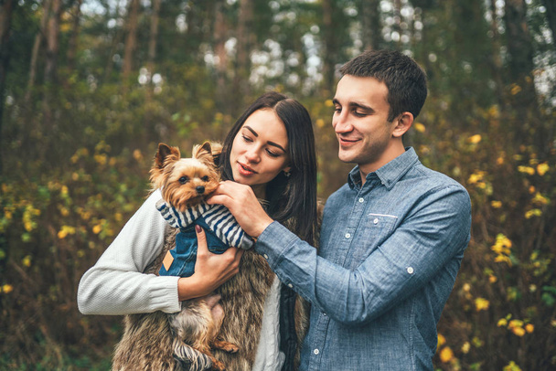 Pretty couple with little yorkshire terrier walking in the forest - Foto, afbeelding