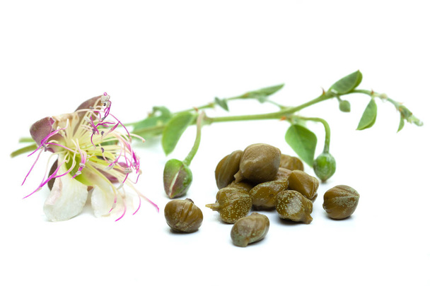Kappertjes gebeitst met plant en caper plant bloem op witte achtergrond - Foto, afbeelding