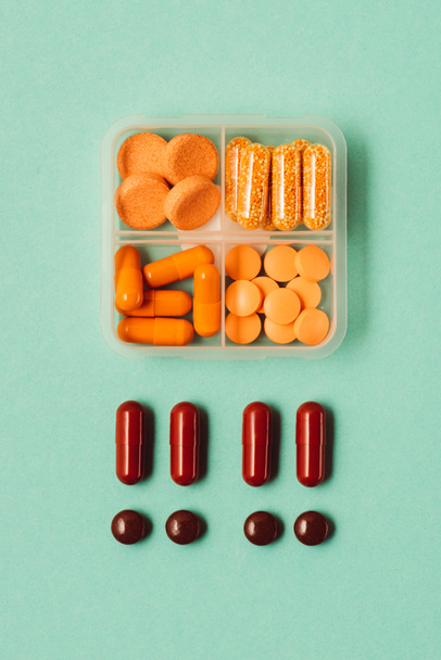 bovenaanzicht van drugs in container, medische pillen en capsules geïsoleerd op groen - Foto, afbeelding