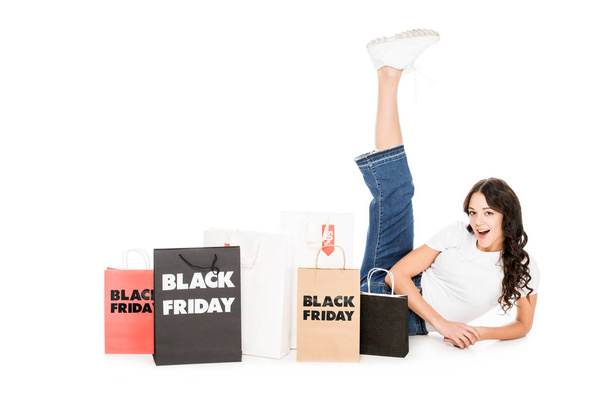 excited girl posing at shopping bags with black friday sale signs isolated on white - Fotoğraf, Görsel