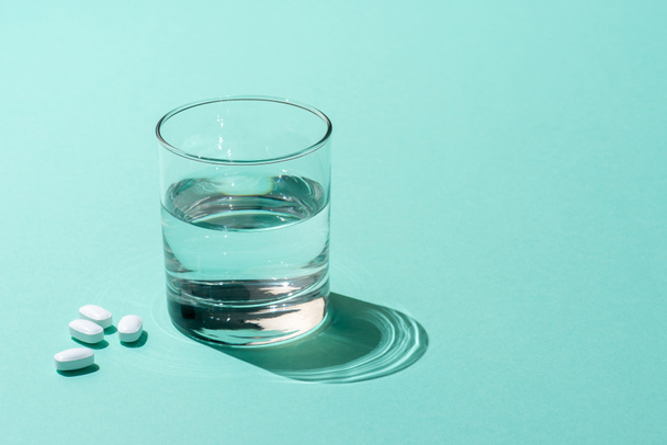 Крупный план стакана воды и медицинских таблеток на зеленом
  - Фото, изображение