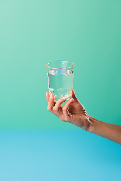 cropped shot of person holding glass of water isolated on green - Photo, Image