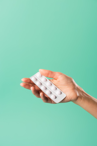 cropped shot of person holding blister pack with tablets isolated on green - Foto, immagini