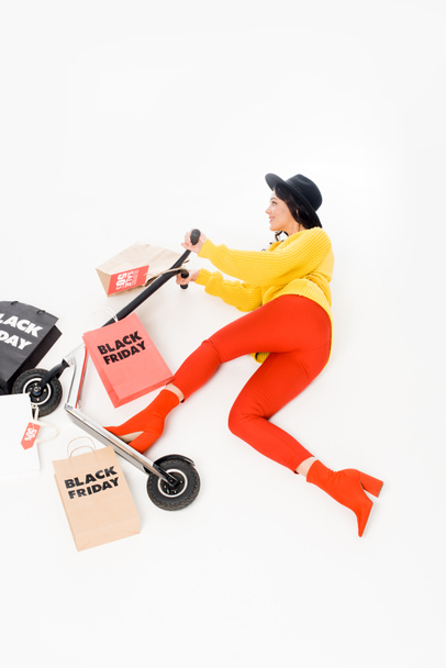 top view of female customer riding scooter with shopping bags for black friday isolated on white - Photo, Image