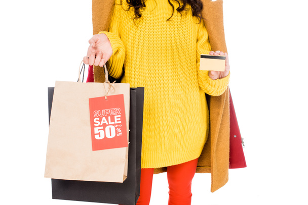 abgeschnittene Ansicht stilvoller Shopaholic mit Kreditkarte und Einkaufstaschen mit Verkaufsetikett auf weißem Grund - Foto, Bild