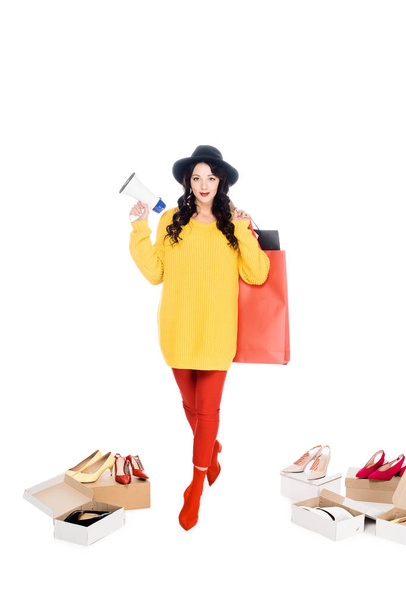 beautiful shopaholic holding megaphone and shopping bags isolated on white with footwear - Foto, Imagem