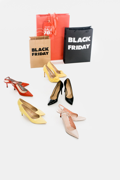 Nahaufnahme weiblicher Schuhe und Einkaufstaschen mit schwarzem Freitag-Schriftzug auf weißem Hintergrund - Foto, Bild