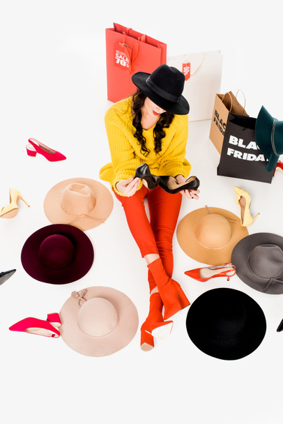 високий кут зору жінки, що сидить на підлозі з взуттям, капелюхами та сумками для покупок з чорною п'ятницею, написи навколо ізольовані на білому
 - Фото, зображення