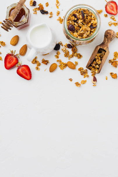 Oatmeal granola with dried fruit, chia seeds and sunflower, honey in glass jar on white background. Top view.  - Foto, imagen