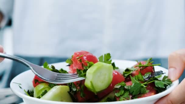 Mujer come crudo tenedor ensalada de pepinos y tomates con verduras en un restaurante de cerca
. - Imágenes, Vídeo
