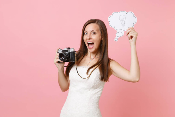Excited bride woman in wedding dress hold retro vintage photo camera, Say cloud speech bubble with lightbulb choosing staff, photographer isolated on pink background. Organization, Wedding to do list - Photo, Image