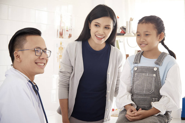 Een mannelijke arts gelukkig beschrijft zijn zoon's gezondheid in de kliniek. - Foto, afbeelding