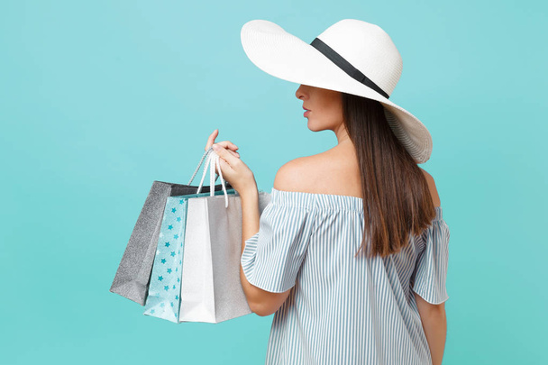 Portrait fashionable elegant fashion beautiful caucasian woman in summer dress, white large wide brim sun hat holding packages bags with purchases after shopping isolated on blue pastel background - Photo, Image