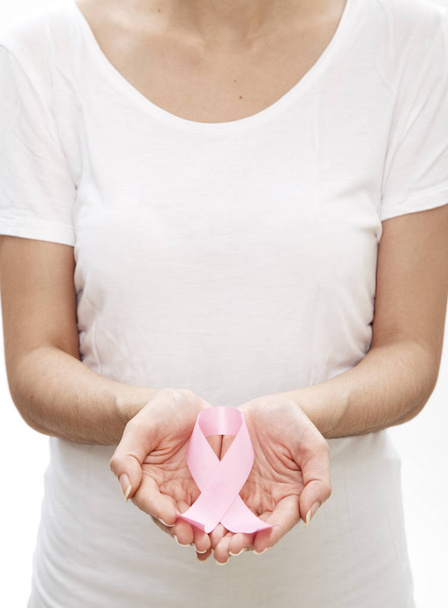 Женщина держит за руку розовую ленту для информирования о раке груди. Здравоохранение и медицина
. - Фото, изображение
