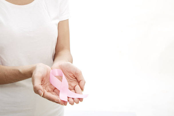 Woman hand holding pink breast cancer awareness ribbon. healthcare and medicine concept. - 写真・画像