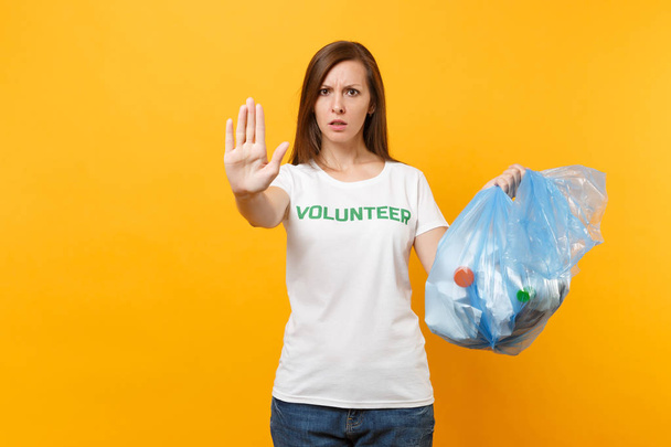 Mulher de t-shirt voluntária, saco de lixo isolado em fundo amarelo. Ajuda gratuita voluntária, graça de caridade. Problema de poluição ambiental. Parar o conceito de proteção ambiental lixo natureza
 - Foto, Imagem