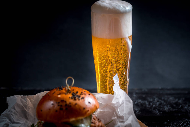 Street food. A big burger with glasses of light beer. On a wooden background. - Foto, Imagen