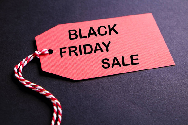 Black friday sale concept. Fourth Friday of November, beginning of Christmas shopping season since 1952. Red tag with black text on bright red background. Copy space, close up, top view, flat lay. - Valokuva, kuva
