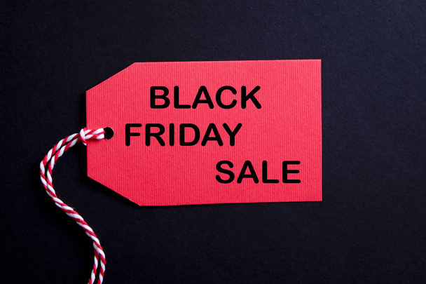 Black friday sale concept. Fourth Friday of November, beginning of Christmas shopping season since 1952. Red tag with black text on bright red background. Copy space, close up, top view, flat lay. - Fotó, kép
