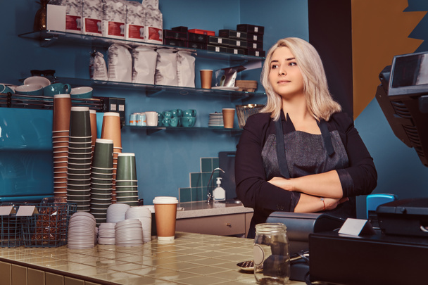 Gyönyörű tapasztalt női barista kötény állandó keresztezett karokkal a kávézóban. - Fotó, kép