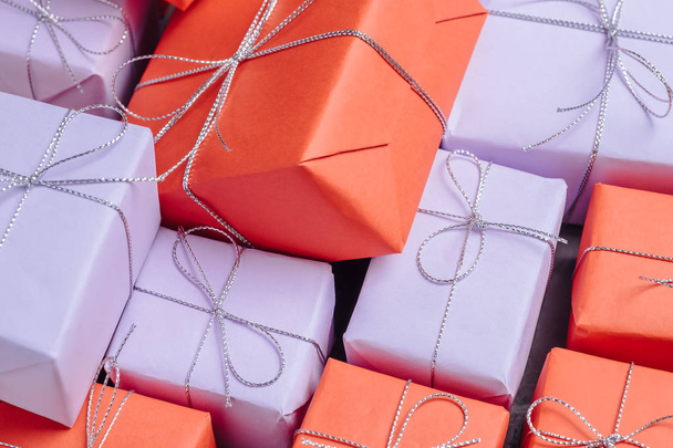 Beaucoup de cadeaux festifs enveloppés dans du papier rouge et lilas et attachés avec de la ficelle d'argent. Cadeaux pour la sélébration. Vue rapprochée
. - Photo, image