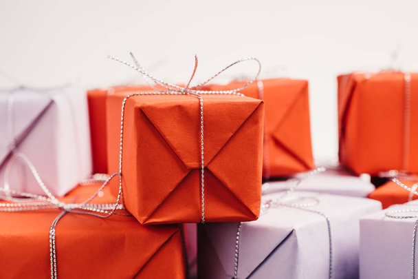 Gift wrapped in red paper and tied with silver twine on white background. Pile presents for mother's day. Close up view, selective focus. - Фото, изображение