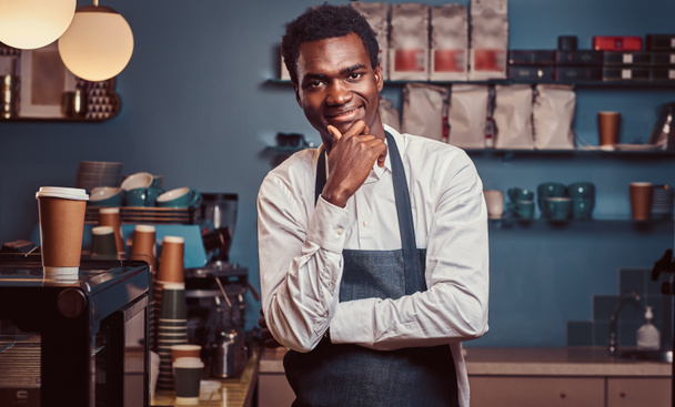 Портрет успешного афроамериканского владельца малого бизнеса, улыбающегося в камеру, стоя в кафе
. - Фото, изображение