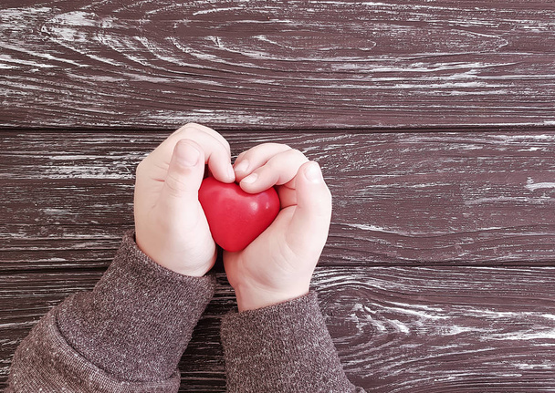 dítě drží červené srdce na dřevěné pozadí konceptu - Fotografie, Obrázek