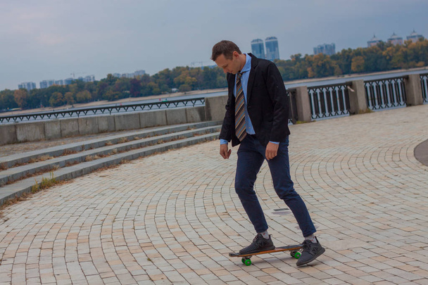 бізнесмен в діловому костюмі в місті зі скейтбордом
 - Фото, зображення