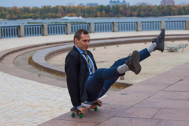 бизнесмен в деловом костюме в городе со скейтбордом
 - Фото, изображение