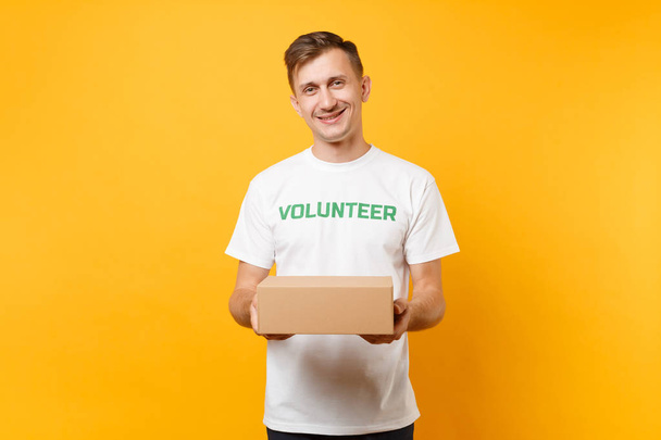 İyi insan beyaz t-shirt ile yazılı yazıt yeşil başlık sarı arka plan izole boş karton kutu ile gönüllü olarak portresi. Gönüllü ücretsiz destek yardım, sadaka zarafet kavramı - Fotoğraf, Görsel
