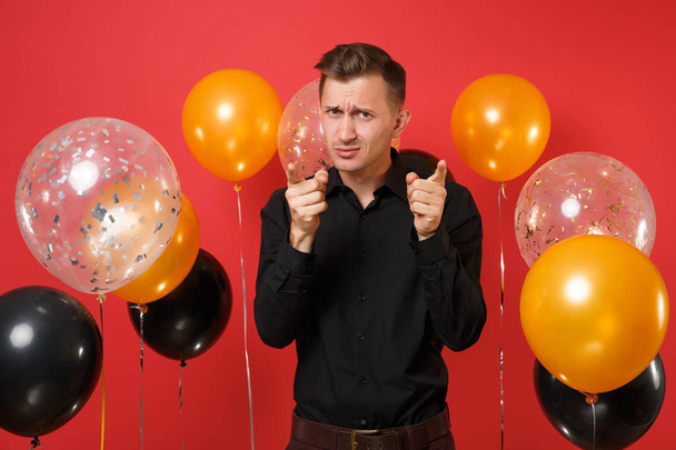 Εν λόγω νεαρός άνδρας στο κλασικό πουκάμισο επισημαίνοντας δάχτυλα δείκτης για την κάμερα σε κόκκινο φόντο αερόστατα. Του Αγίου Βαλεντίνου, Διεθνές Γυναικείο ημέρα, ευτυχισμένο το νέο έτος, γενέθλια mockup διακοπών κόμμα έννοια - Φωτογραφία, εικόνα