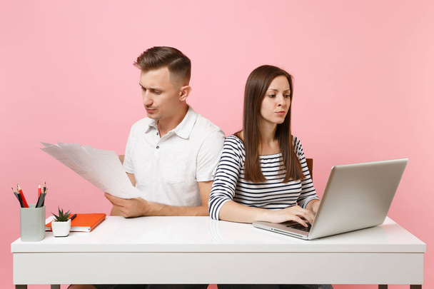 2 人の若い怒っているビジネス女性男性同僚パステル ピンクの背景に分離された現代のラップトップ ホワイト デスクで仕事を座る。達成のキャリアの概念。コピー スペース広告、若者の共同作業 - 写真・画像