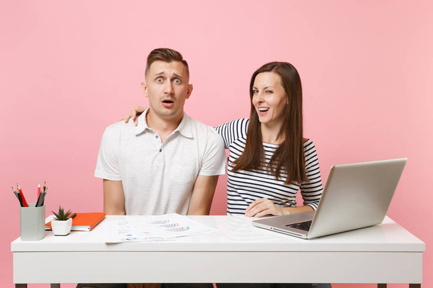 Two young business woman man colleagues sit at white desk isolated on pastel pink background. Sexual harassment, assault lustful boss, intimidation, work ethic, stress, design concept. Co working - Photo, Image