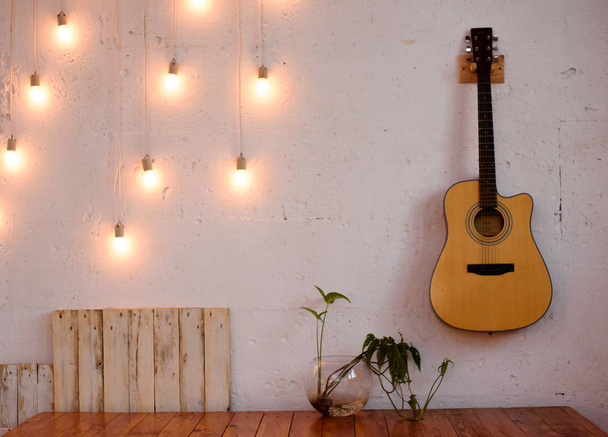 The textured white wall is decorated with yellow lights and a guitar. - Foto, afbeelding