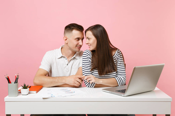 Two young tender business woman man colleagues sit work at white desk with contemporary laptop isolated on pastel pink background. Achievement career concept. Copy space advertising, youth co working - Foto, Imagen