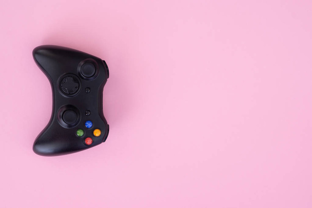 Zwarte joystick op pastel roze achtergrond. Gamepad is geïsoleerd op een roze achtergrond. Gaming competitie. Gamer concept. Controller voor videospelletjes. Copyspace - Foto, afbeelding