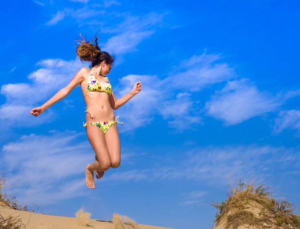 Aantrekkelijk meisje in Bikini springen op het strand Having Fun, zomervakantie vakantie levensstijl. Gelukkig vrouwen springen vrijheid op zand. - Foto, afbeelding