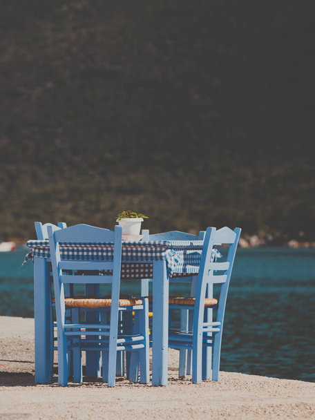 Mesa azul junto al mar y sillas cafetería abierta restaurante al aire libre en Grecia en la orilla del mar. Vacaciones de verano en resort. - Foto, imagen