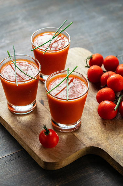 Seasonal tomato soup gazpacho in glasses on dark wooden table background. Vertical. Food and drink, still life, diet and nutrition concept. Meditteranean food. - Photo, Image