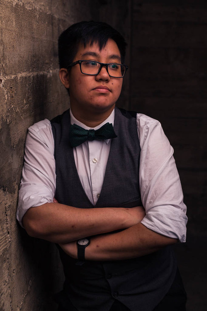 Young transgender man in formal clothing poses in a grungy urban location - 写真・画像