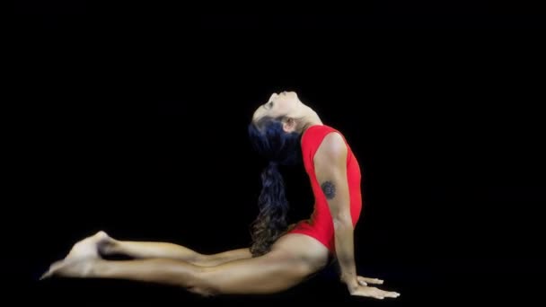 Νεαρή γυναίκα να κάνει Γιόγκα ασκήσεις σε μαύρο φόντο - Πλάνα, βίντεο