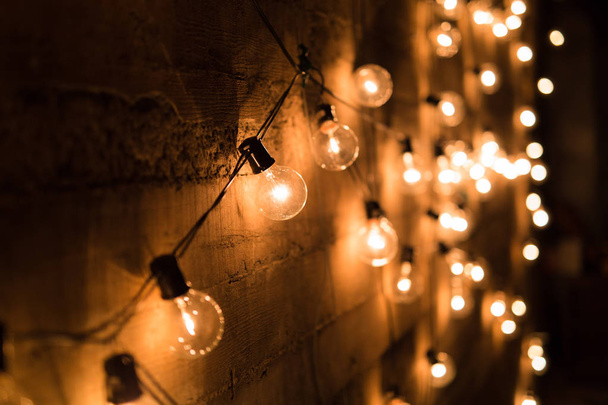 Corda de lâmpadas vintage contra uma parede de concreto com deve
 - Foto, Imagem