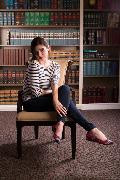 Young caucasian woman dressed in mid century casual fashion poses in a library - Photo, Image