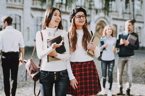 Happiness. Girls. Happy Together. Students. Courtyard. Books. Standing in University. Good Mood. University. Knowledge. Architecture. Intelligence. Diploma. Celebration. Campus. Man. Friends. Happy. - Foto, imagen