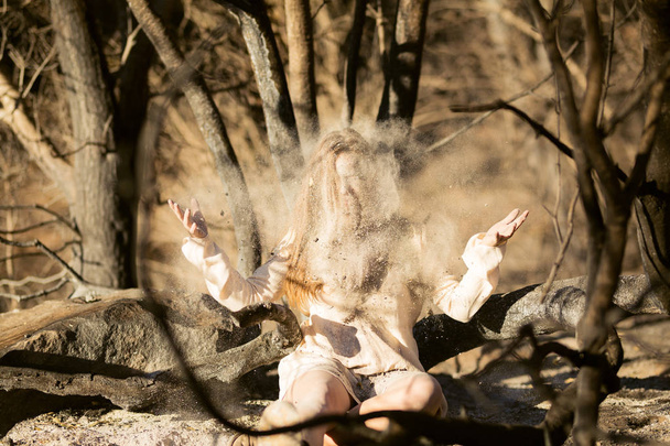 Крупный план молодой смешанной расы женщина в белом платье играет с волосами возле леса уничтожены лесным пожаром, в то время как покрыты пеплом
 - Фото, изображение